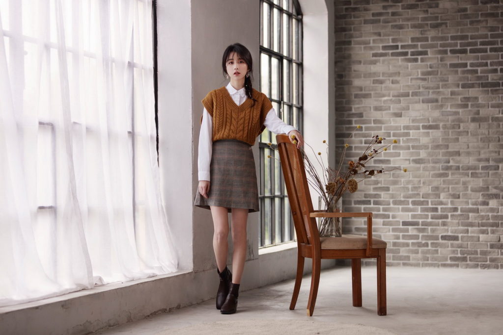 GU「品牌好友」邵雨薇本次以褐色的「短版粗紡針織背心」搭配經典長袖白襯衫以及格紋迷你裙,展現氣質甜美的零失誤好感穿搭。